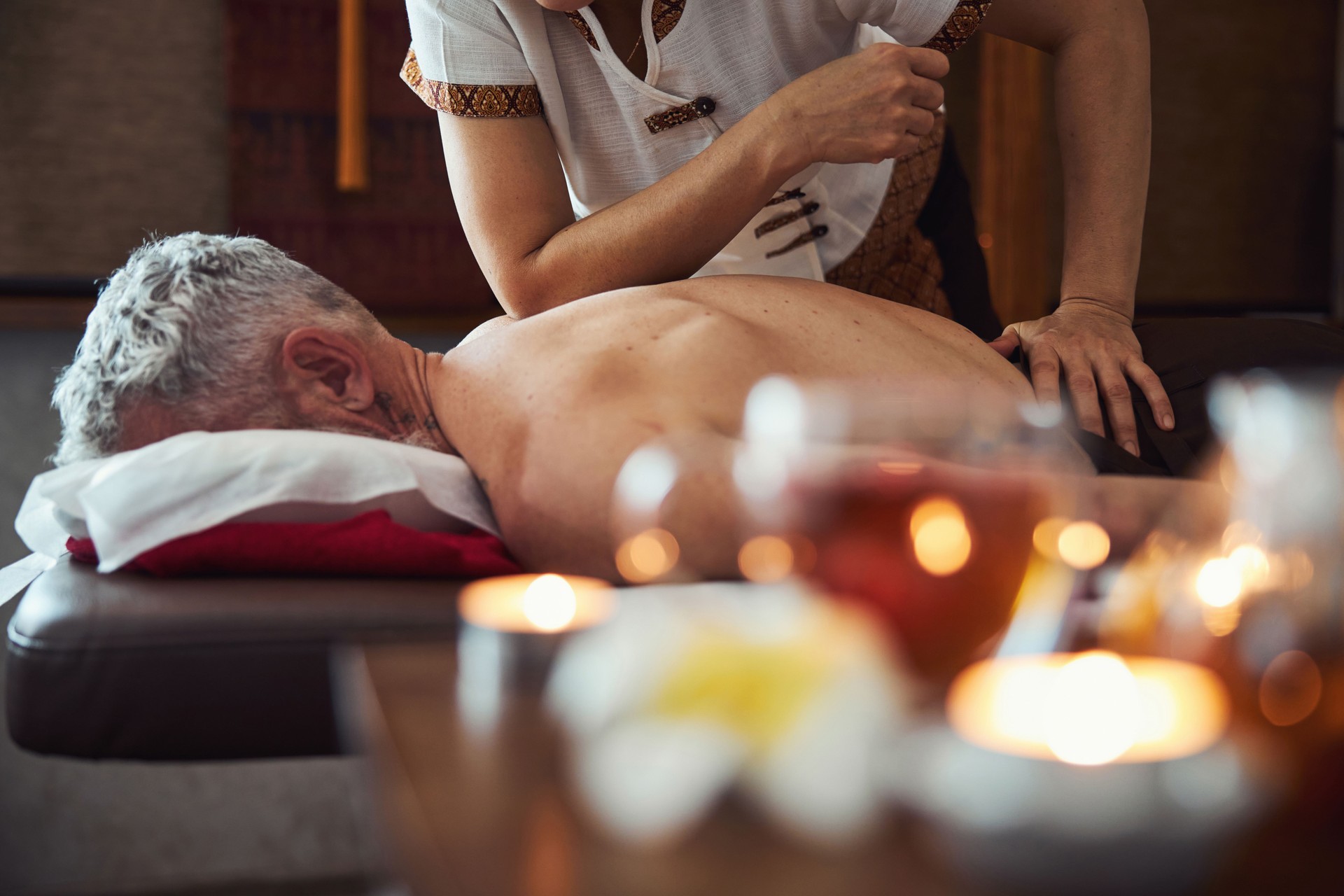 Thai manual therapist healing male back in studio
