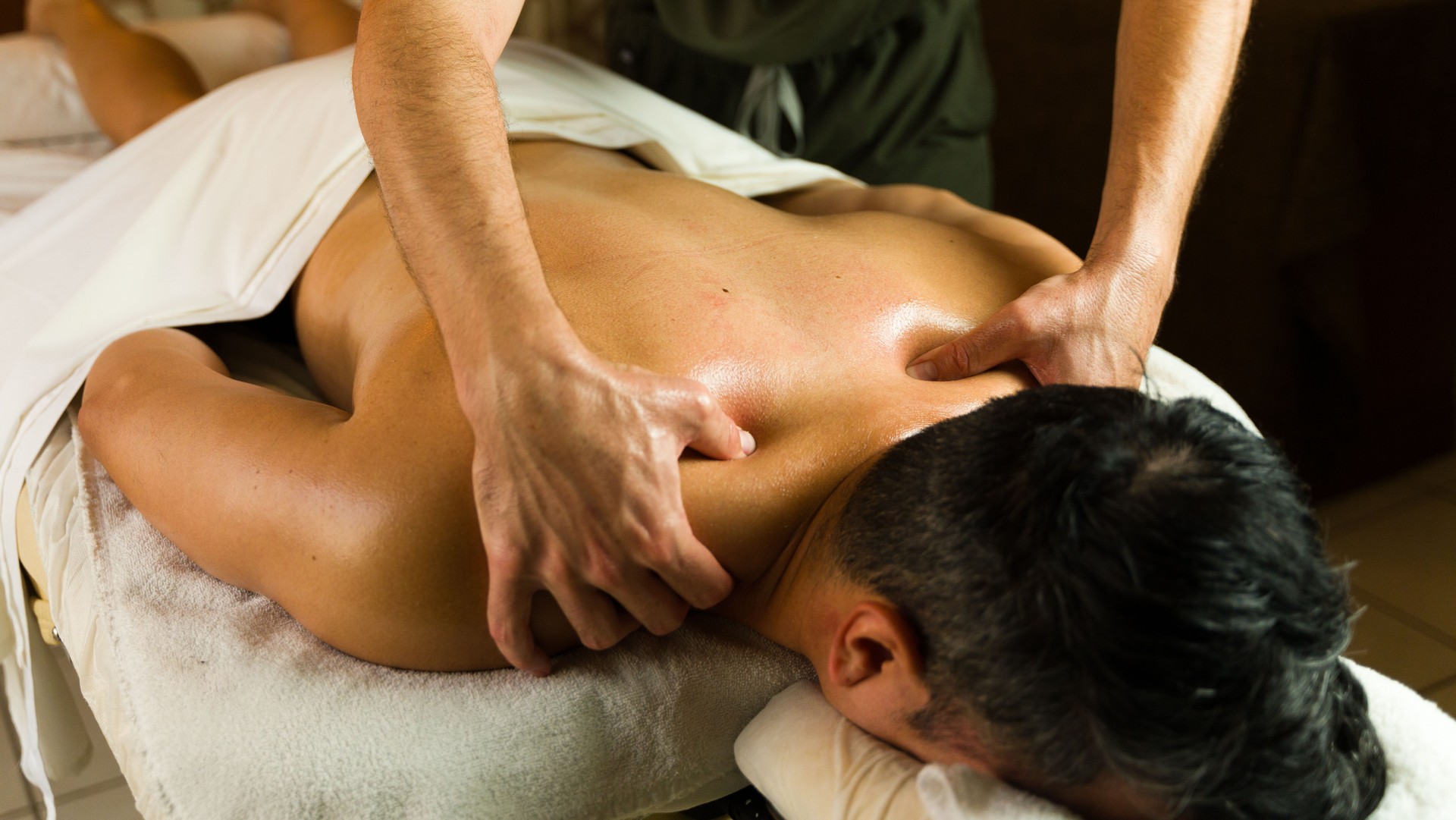 Man receiving a relaxing back massage from a male masseur on a massage table in a spa